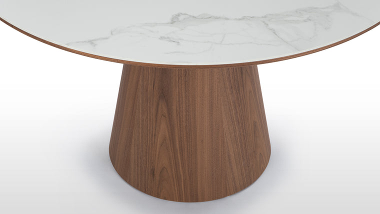 Contrasting Materials | Crafted with a choice of ceramic or white translucent glass for the tabletop, paired with a rich walnut base, the Cella Dining Table showcases a striking contrast between the sleek surface and the natural wood grain, adding warmth and texture to its refined form.
