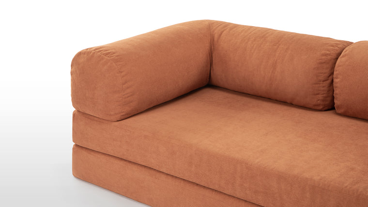 Textured Warmth | The Teddy Sofa’s orange corduroy upholstery not only adds a pop of vibrant color but also enhances the cozy, inviting feel with its soft, ribbed texture. The plush oversized cushions ensure a snug seating experience, while the contrasting metal frame accents add a touch of industrial chic. This combination of materials creates a stylish yet warm aesthetic, making it a statement piece in any modern home.
